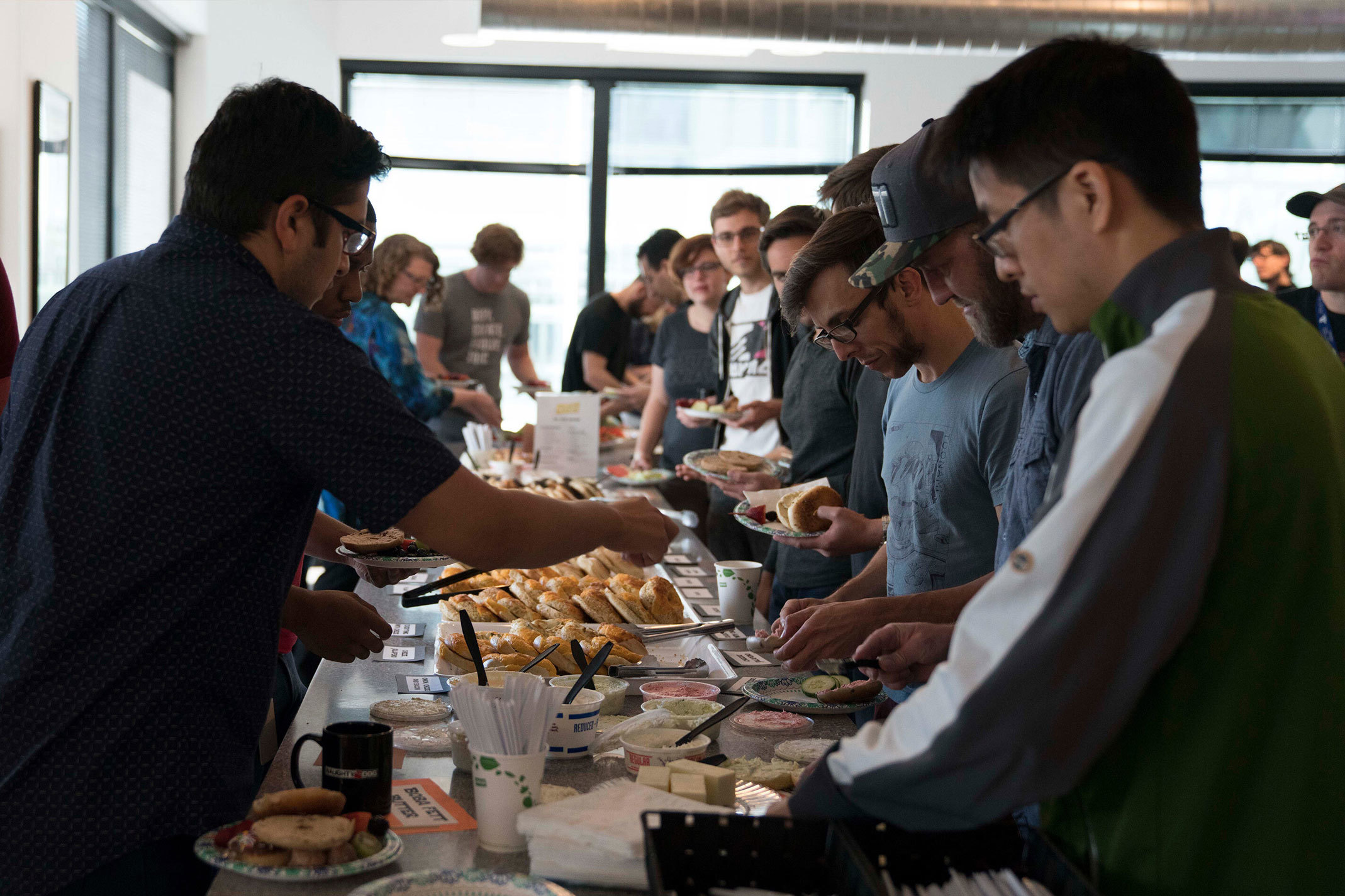 A large group of developers gathered around a buffet in the studio kitchen